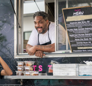 image of foodtruck vendor with his head outside of window talking to a customer